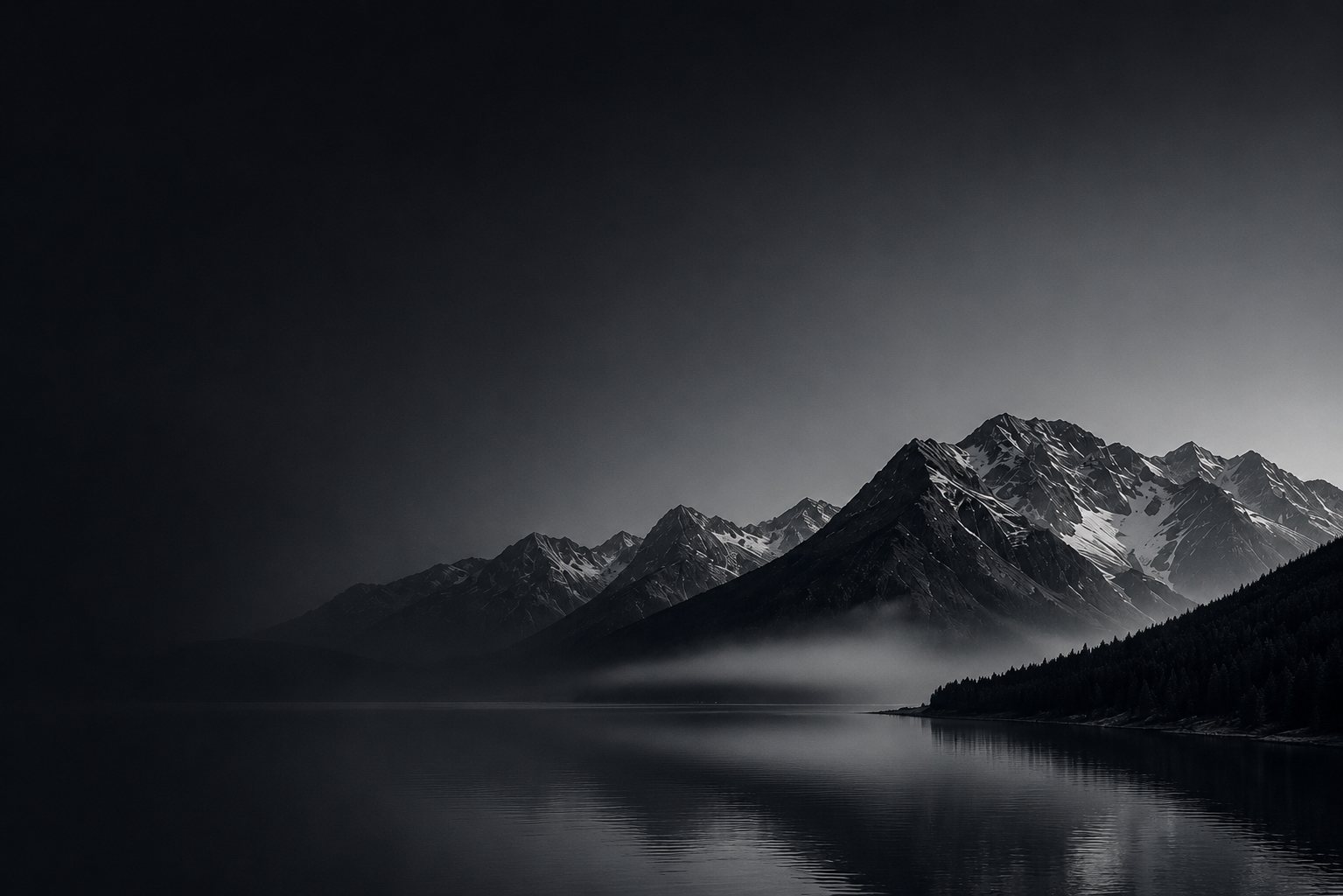 Misty mountains over a still lake at dusk
